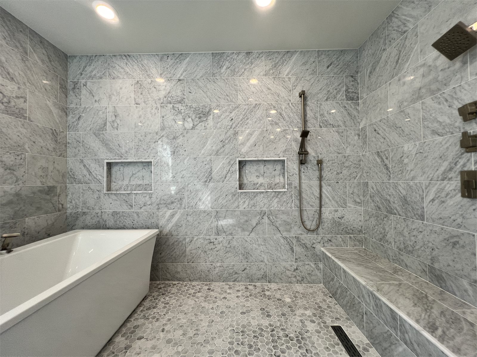 Full bathroom with a walk-in shower in white marble-look tile and a double vanity