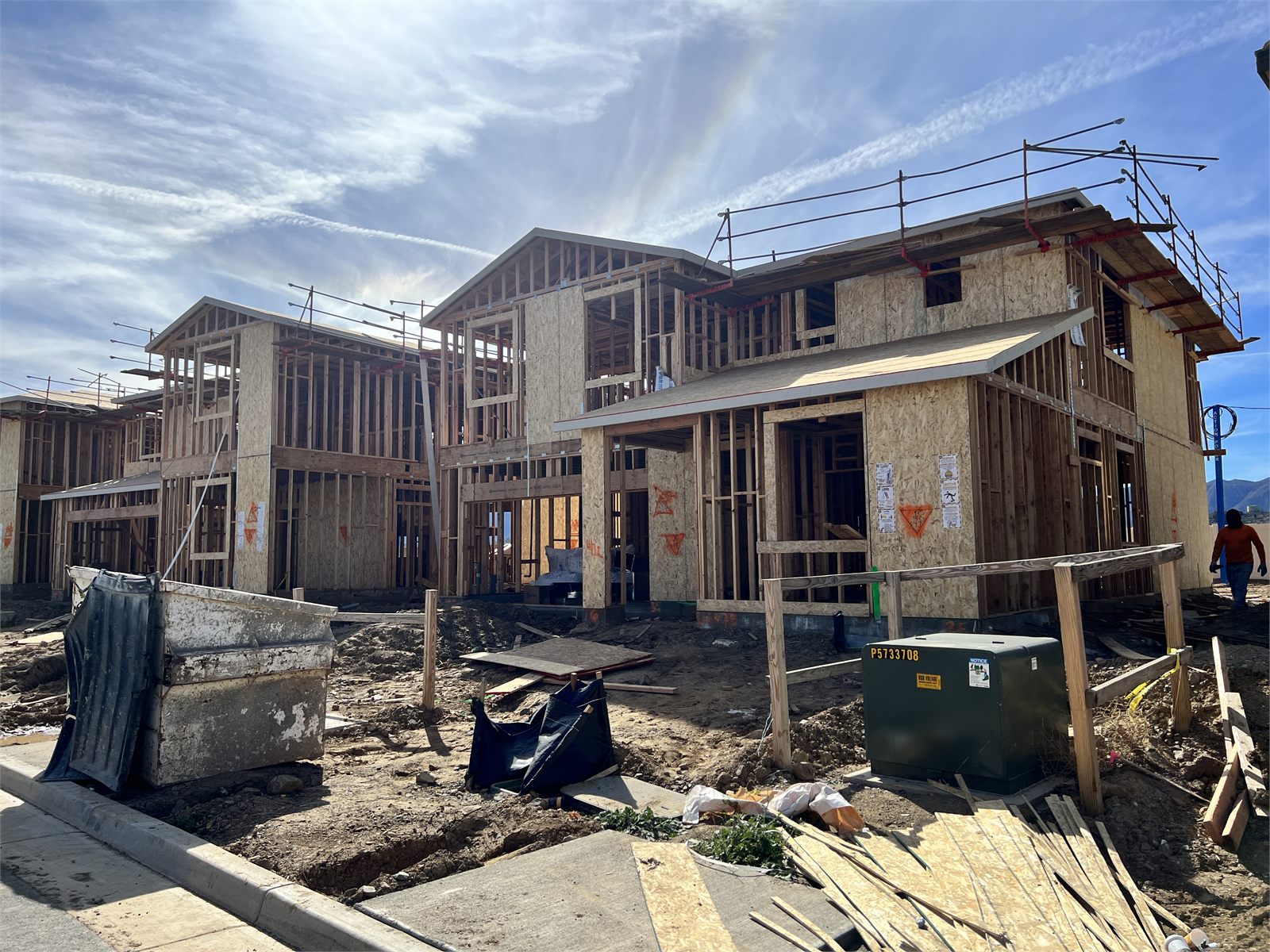 Two-story home in framing and sheathing, with scaffolding and an exterior staircase on site